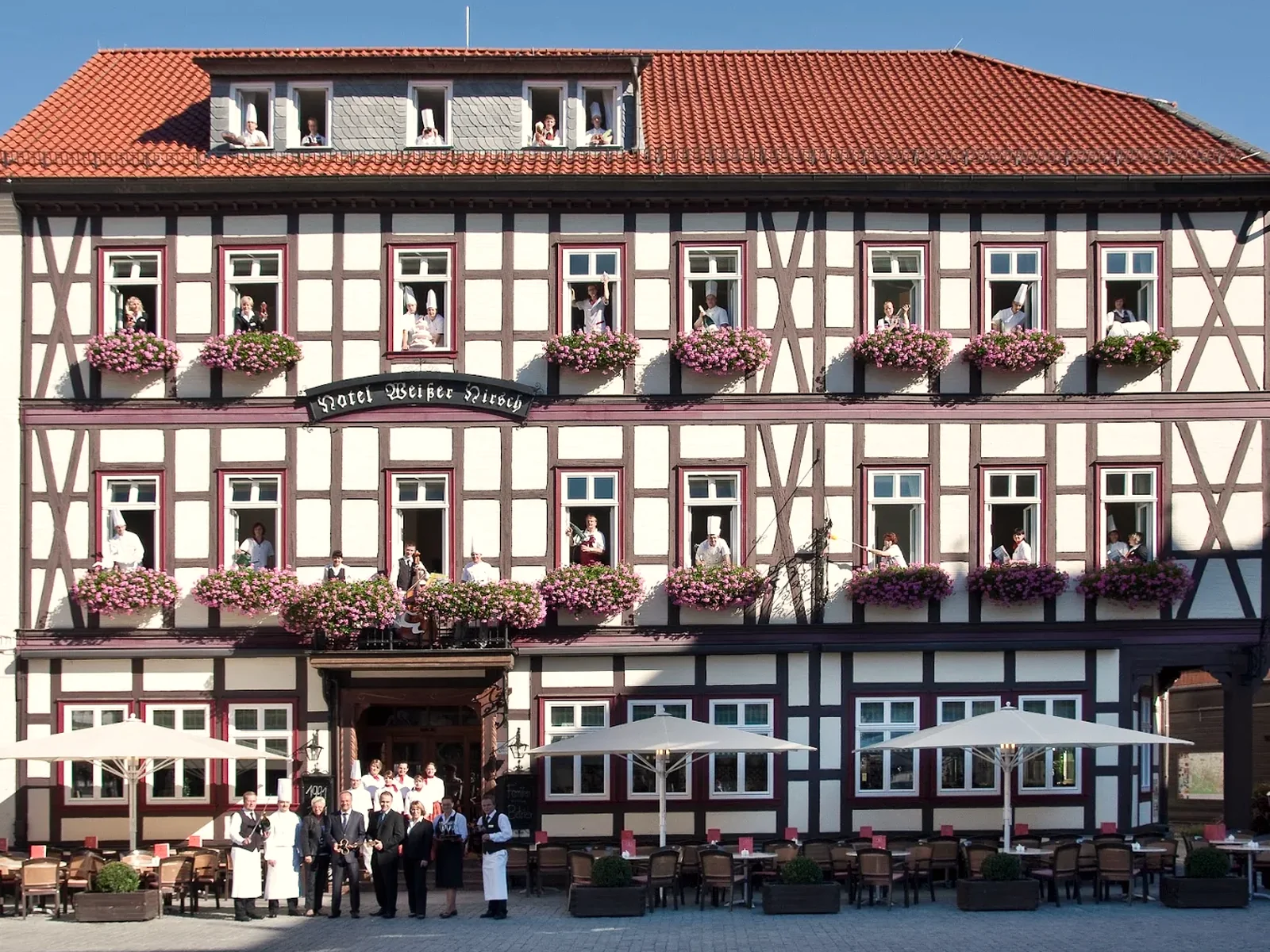 Das Team des Weißen Hirsch in den Fenstern der Fachwerkfassade